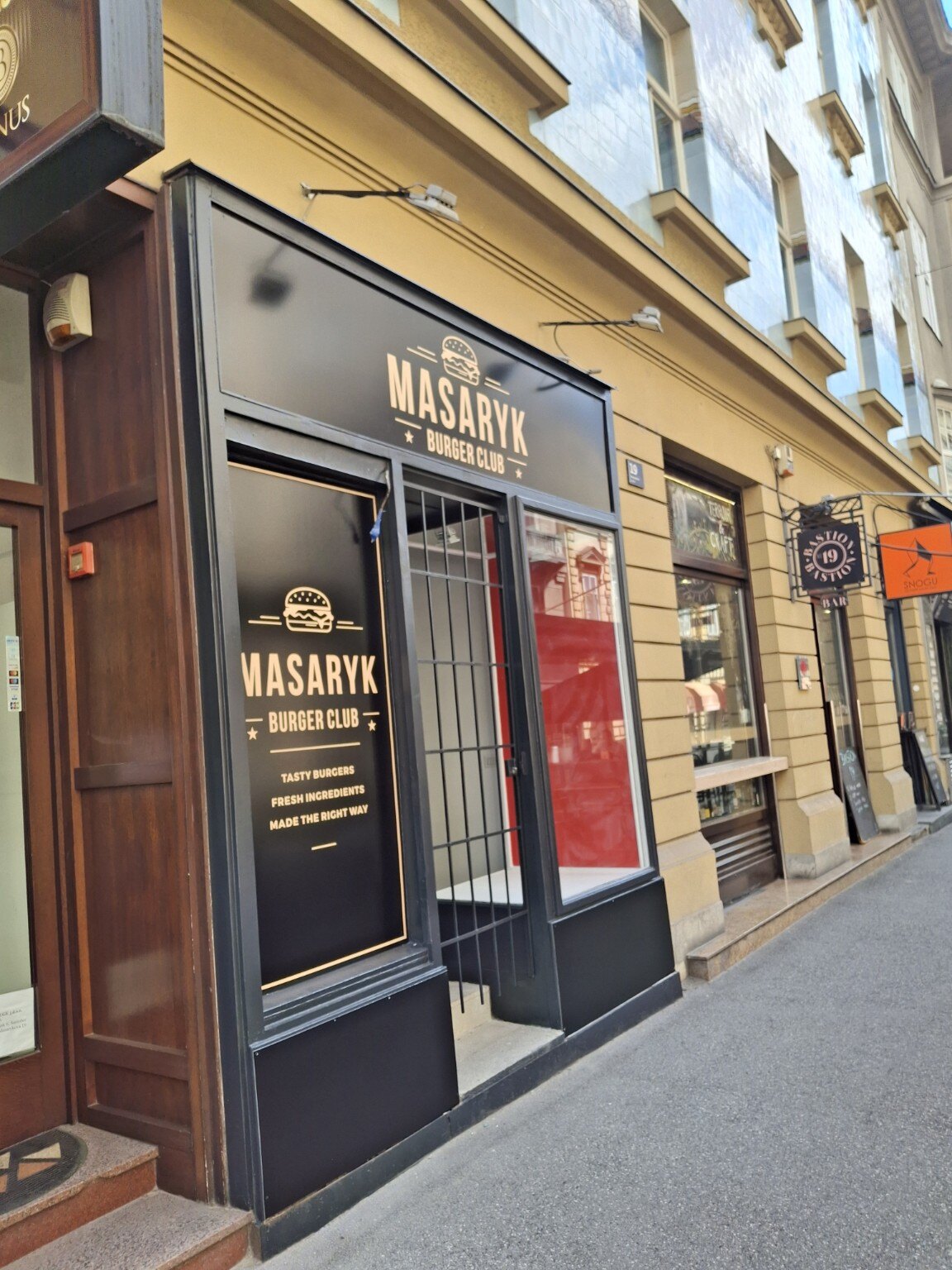 Pogled iz kuta na dovršeno pročelje Masaryk Burger Cluba s vidljivim crvenim interijerom